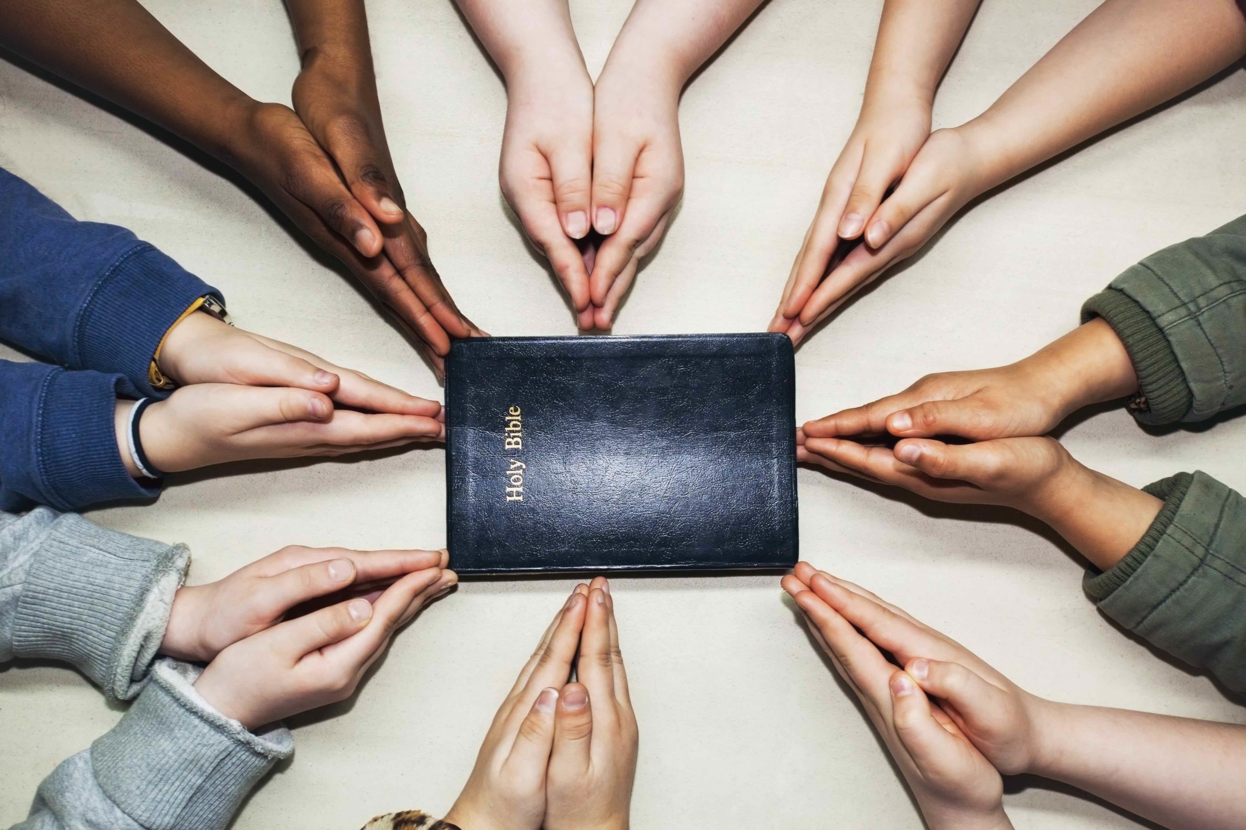 Multicultural hands around bible scaled