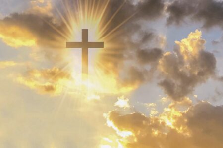 Picture of Christian cross appears bright in the gold sky in the page Easter invokes grand themes