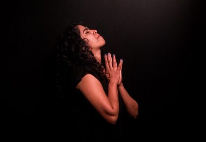 Picture of Woman praying in shaft of light in the page Write of Passage: Rev Angie Griffin